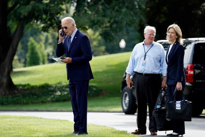 Mike Donilon and Liz Sherwood-Randall watch as President Joe Biden speaks on his cellphone on the White House grounds in August 2024.