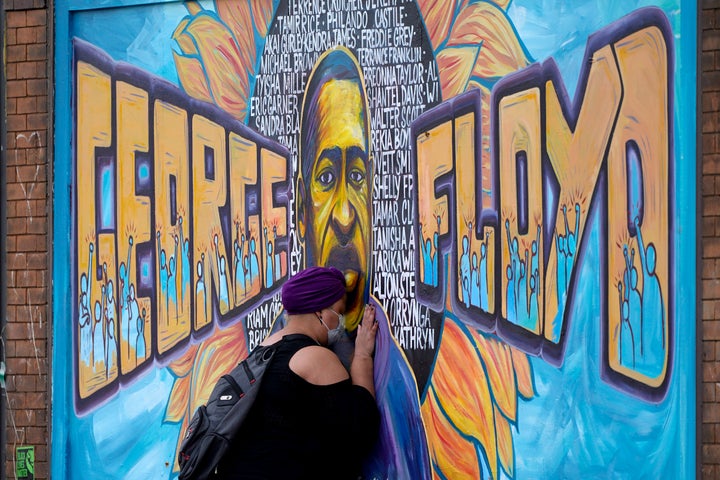 Damarra Atkins pays respect to George Floyd at a mural at George Floyd Square, Friday, April 23, 2021, in Minneapolis. (AP Photo/Julio Cortez, File)