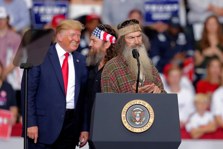 President Donald Trump laughs with Willie Robertson, of the reality TV series "Duck Dynasty," and Phil Roberston, the family patriarch, right, at a campaign rally in 2019.