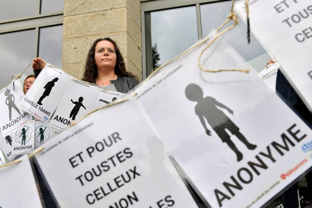 Μια γυναίκα κοιτάζει πίσω από ένα πανό που εκπροσωπεί ανώνυμα θύματα κατά τη διάρκεια διαδήλωσης πριν από την ετυμηγορία στη δίκη του Joel Le Scouarnec, ενός 74χρονου πρώην χειρουργού, ο οποίος κατηγορείται για βιασμό και σεξουαλική κακοποίηση 299 παιδιών, την Τετάρτη 28 Μαΐου 2025 στο Vannes της Βρετάνης, στη δυτική Γαλλία. (AP Photo/Mathieu Pattier)