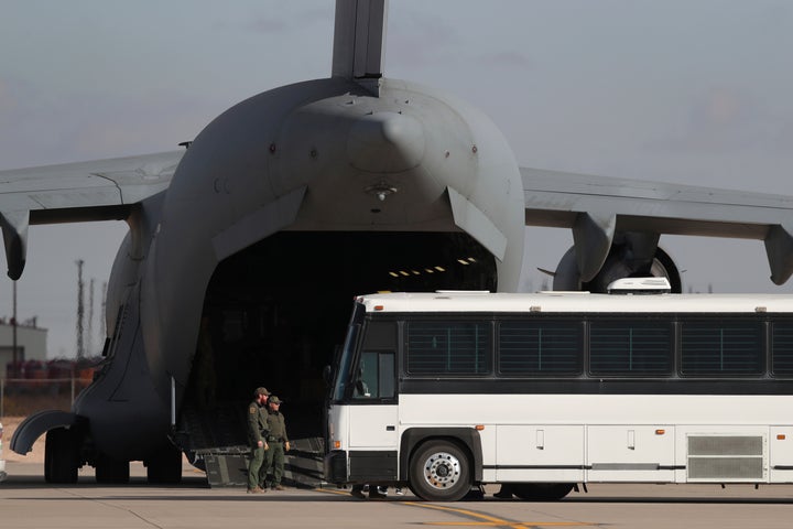 A military aircraft waits for migrants to board from a bus at Fort Bliss in El Paso on Jan. 30, before deporting them to Guatemala.