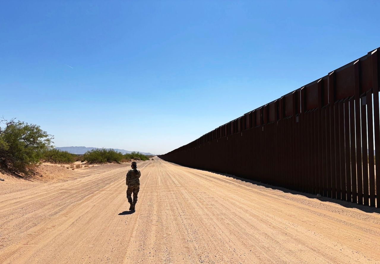 A soldier walks beside a section of border wall in Doña Ana County, New Mexico.