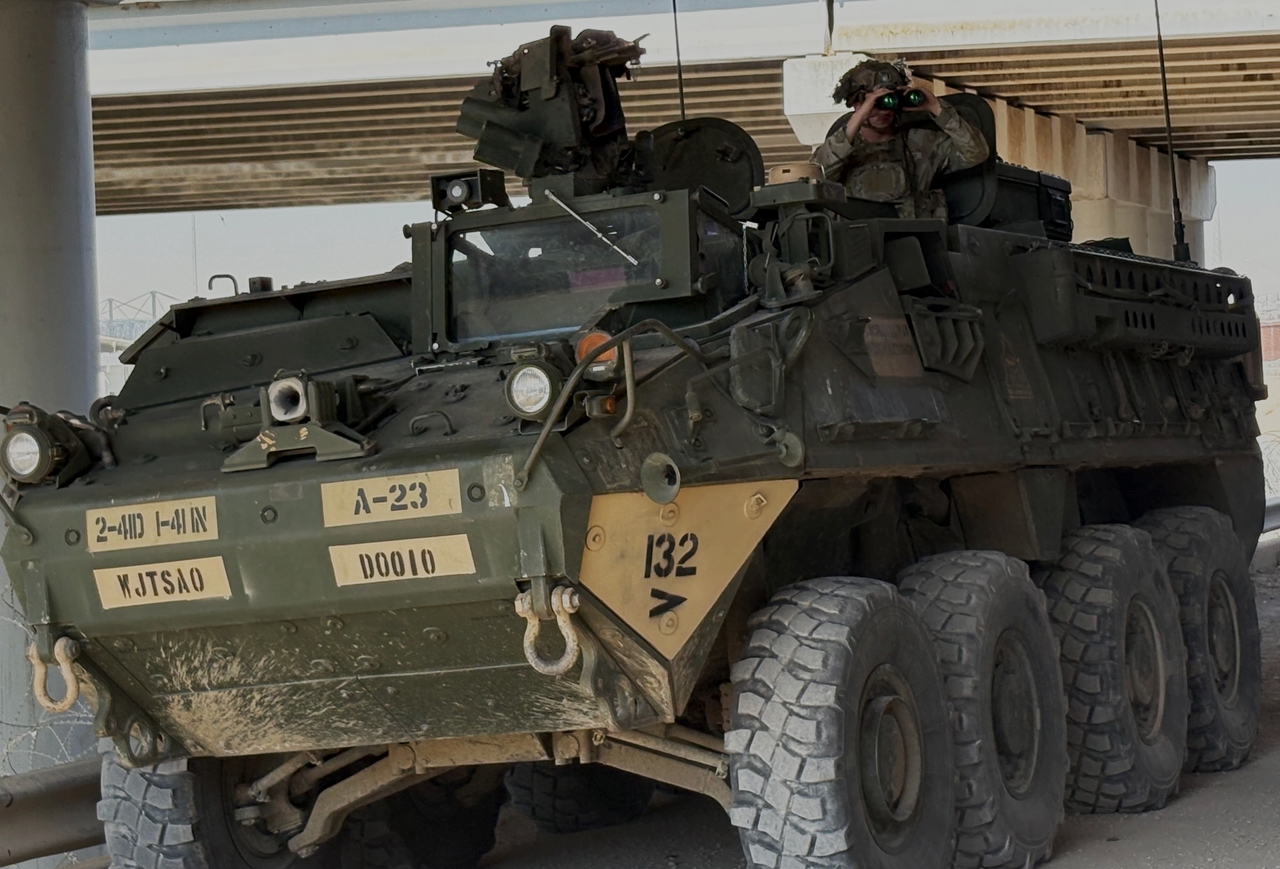 A soldier emerges from an armored Stryker vehicle and looks north underneath the Bridge of the Americas in El Paso, Texas.