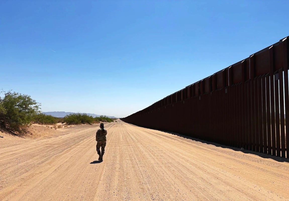 A soldier walks beside a section of border wall in Doña Ana County, New Mexico.(Matt Shuham/HuffPost)
