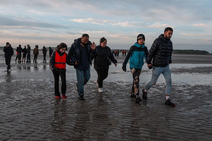 People walk into the sea as they prepare to board a migrant dinghy yesterday in Gravelines, France. The numbers of migrants crossing the English Channel in small boats is up roughly 40% on last year. 