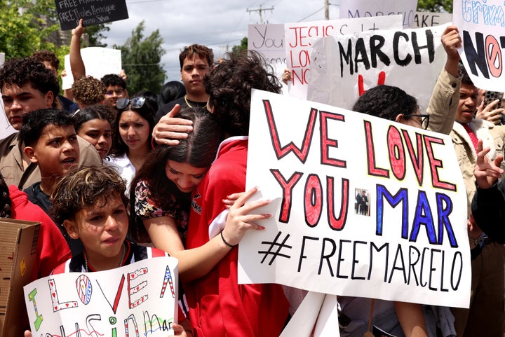 Family and classmates of Marcelo Gomes Da Silva embrace as they protest outside of Milford Town Hall on Sunday.