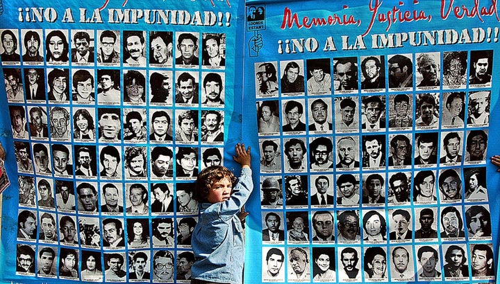 A boy holds a banner with pictures of some of the people killed or disappeared during Augusto Pinochet's dictatorship from 1973 to 1990.