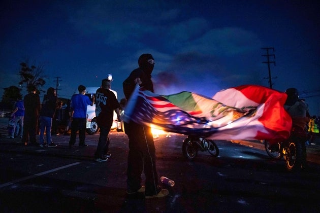 A demonstrator waves an U.S. and Mexican flag during a protest in Compton, Calif., Saturday, June 7, 2025, after federal immigration authorities conducted operations. (AP Photo/Ethan Swope)