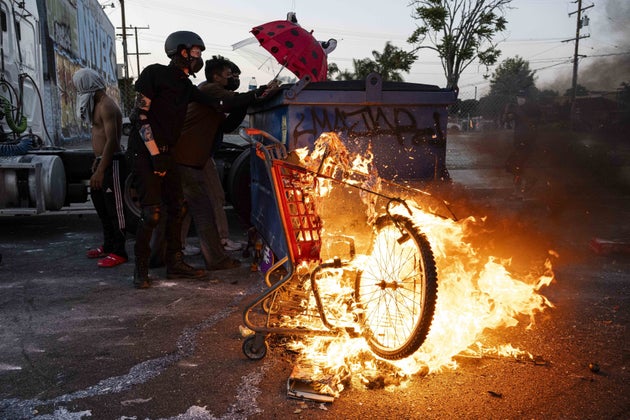 PARAMOUNT, CALIFORNIA - JUNE 7: A shopping cart is seen on fire as protesters shield themselves from flash bang grenades shot by the Sheriffs Department after Immigration and Customs Enforcement (ICE) agents and Department of Homeland Security (DHS) officers made raids of illegal immigrants in Paramount, California, United States on June 7, 2025. (Photo by Jon Putman/Anadolu via Getty Images)