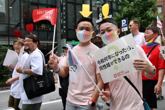 「私たちはここにいる」と伝えるように、矢印のメッセージをつけてパレードを歩く人たちも