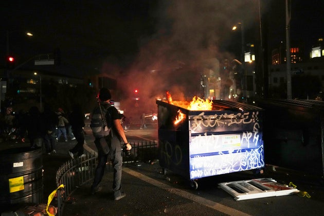 Διαδηλωτές βάζουν φωτιά σε κάδο απορριμμάτων κοντά στο μητροπολιτικό κέντρο κράτησης στο κέντρο του Λος Άντζελες, Κυριακή 8 Ιουνίου 2025. (AP Photo/Eric Thayer)