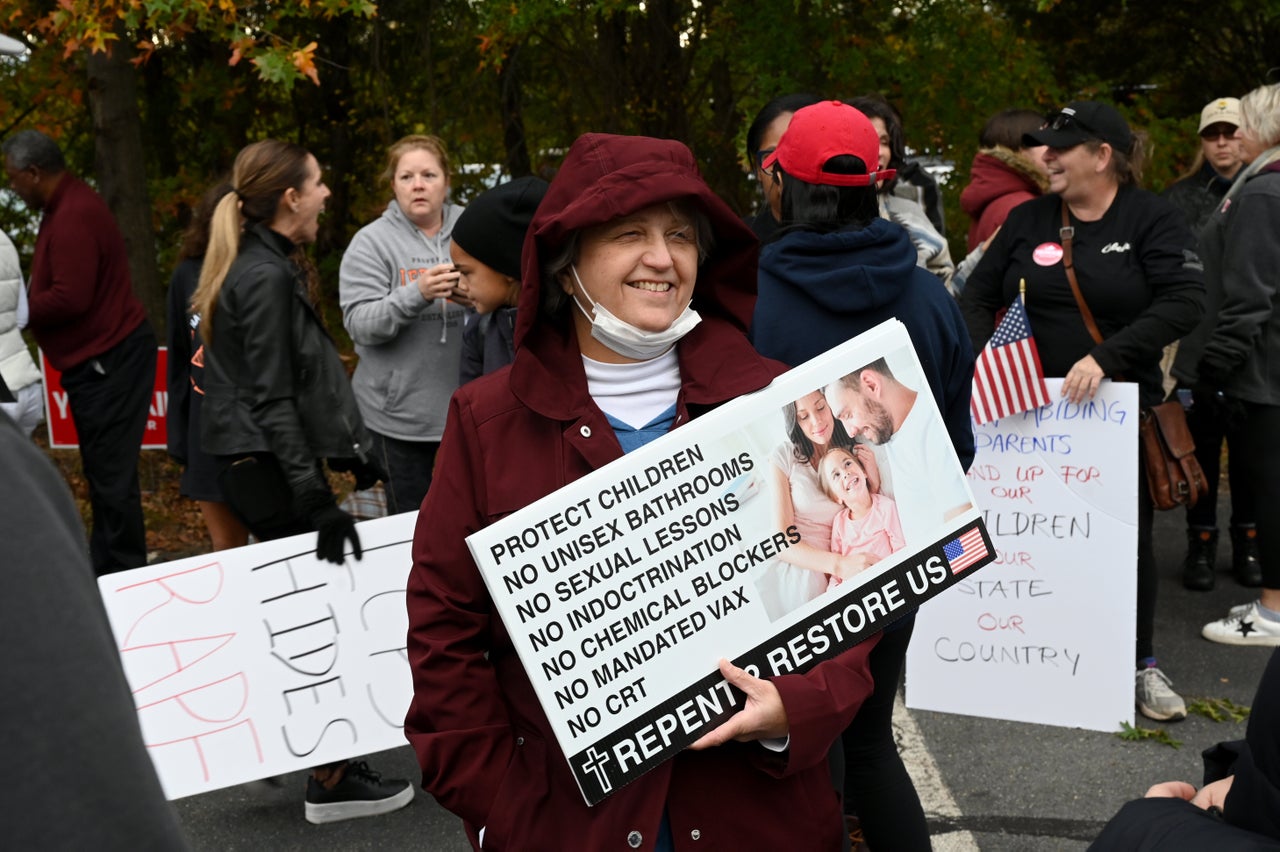Trump Is On Observe To Make This Racist Downside Even Worse 1 A woman holds a sign listing conservative talking points ahead of a school board meeting in Loudoun County, Virginia.