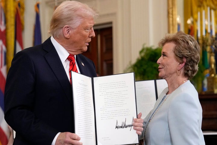 President Donald Trump holds up a signed executive order alongside Secretary of Education Linda McMahon.