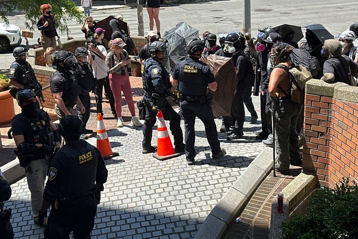 Protesters face off with officers with Federal Protective Service outside a blocked exit at the Immigration Court on Tuesday, June 10, 2025, in Seattle. (AP Photo/Martha Bellisle)