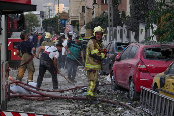 Firefighters and people clean up the scene of an explosion at a residence compound after Israeli attacks in Tehran, on June 13, 2025.