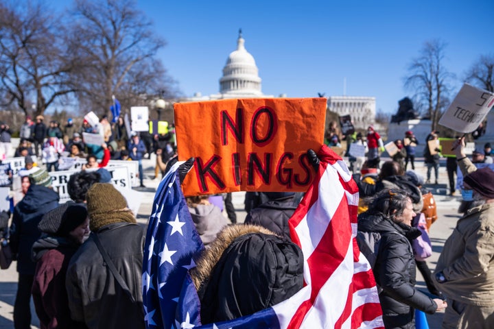 Above, demonstrators hold signs during a protest to oppose the Trump administration's policies in February. Security experts strongly recommend disabling biometrics off of your phone if you go to a protest.