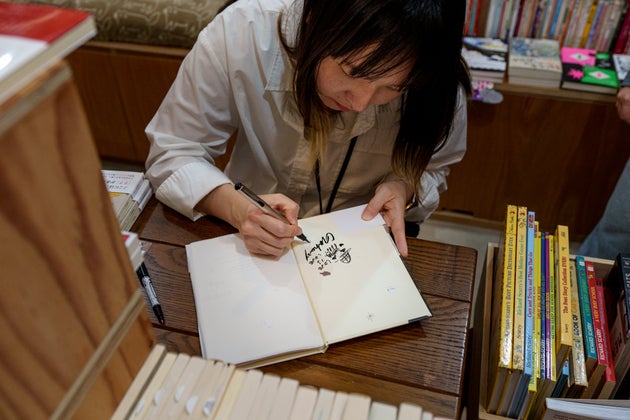 猫本専門店「Cat's Meow Books（キャッツミャウブックス）」で自著にサインする、カヒジさん