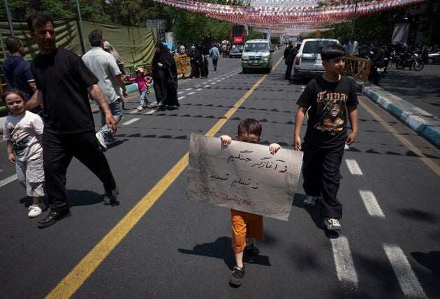 イラン・テヘラン中心部で行われた抗議集会で、「戦争を仕掛けたのは私たちではない、脅迫に屈しない」と書かれたプラカードを掲げる子ども（2025年6月13日）