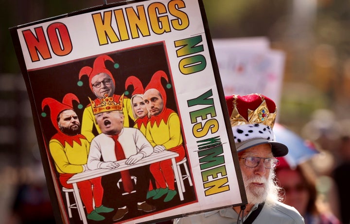 Um homem em Tucson, Arizona, usa uma coroa, carrega uma placa representando Donald Trump como um rei cercado por idiotas da corte.