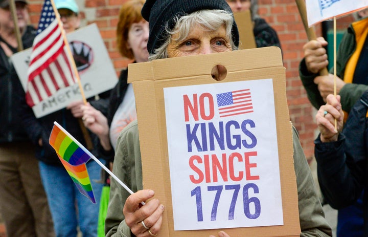 A demonstrator outside of the train station in Bellows Falls, Vermont, holds a sign reading, "No Kings Since 1776."