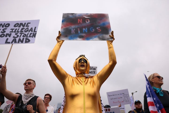 Um manifestante da Filadélfia, vestido com ouro, segura uma leitura de placas 