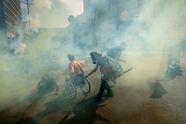 People move through tear gas during a protest Saturday, June 14, 2025, in Los Angeles. (AP Photo/Noah Berger)