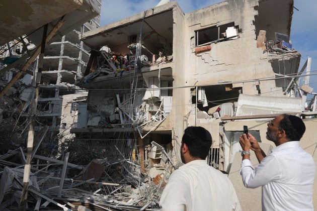 People inspect a destroyed building that was hit by a missile fired from Iran, near Tel Aviv, Israel, Sunday, June 15, 2025. (AP Photo/Ariel Schalit)