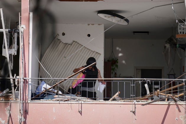 Ένας άνδρας ανασύρει αντικείμενα από ένα διαμέρισμα που υπέστη ζημιές στο σημείο όπου χτύπησε ιρανικός πύραυλος στη Χάιφα του Ισραήλ, Δευτέρα 16 Ιουνίου 2025. (AP Photo/Ariel Schalit)