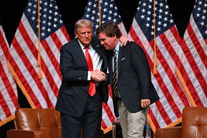 Trump and Carlson shake hands during a 2024 campaign stop.