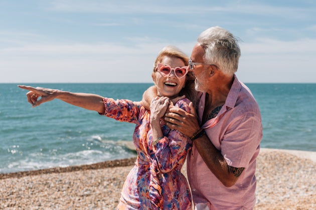 An affectionate older couple enjoys a carefree moment at the beach on a sunny day.