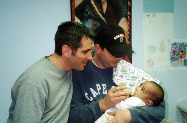 （左から）ダニー・スチュワートとピーター・マキューリオ。ふたりの子どもとなる赤ちゃんを抱く。2000年に撮影