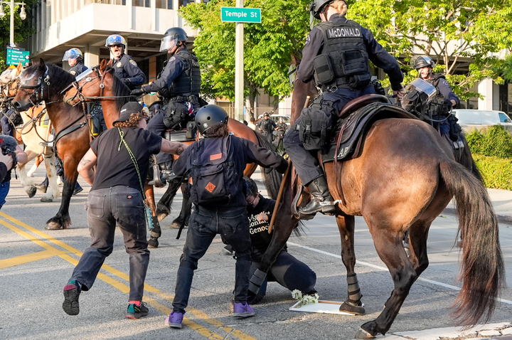 Police use horses to push back demonstrators near City Hall, Wednesday, June 11, 2025, in Los Angeles.