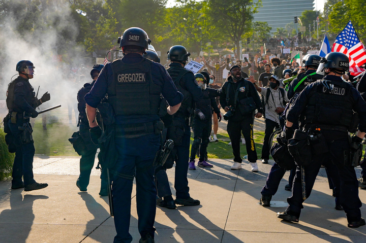 Police fire flashbangs and move into a crowd of demonstrators near City Hall on Wednesday, June 11, 2025, in Los Angeles.