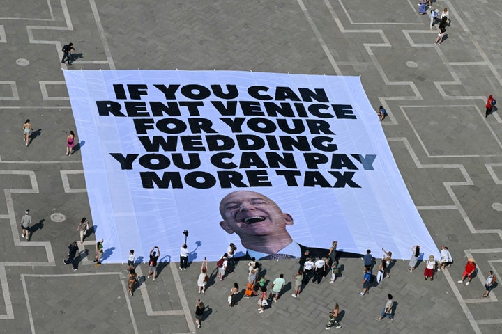 Activists of international environmental group Greenpeace deploy a giant banner displaying a picture of Jeff Bezos and reading "If you can rent Venice for your wedding you can pay more tax" at St Mark square in Venice on June 23, 2025.