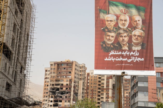 ΤΕΧΡΑΝΗ, ΙΡΑΝ - 26 ΙΟΥΝΙΟΥ: Ένα πολιτικό πανό κρέμεται κοντά στα απομεινάρια ενός κτιρίου κατοικιών στη συνοικία Saadat Abad της Τεχεράνης, το οποίο χτυπήθηκε από ισραηλινή επίθεση στις 13 Ιουνίου, με αποτέλεσμα το θάνατο του Δρ Τεχεράνι, προέδρου του Πανεπιστημίου Αζάντ, και 16 πολιτών στις 26 Ιουνίου 2025 στην Τεχεράνη του Ιράν. Η κατάπαυση του πυρός μεταξύ του Ισραήλ και του Ιράν έθεσε τέρμα στις 12 ημέρες καθημερινών αεροπορικών επιθέσεων που ξεκίνησαν με τα πλήγματα του Ισραήλ κατά των ιρανικών στρατιωτικών και πυρηνικών εγκαταστάσεων στις 13 Ιουνίου. (Φωτογραφία: Majid Saeedi/Getty Images)