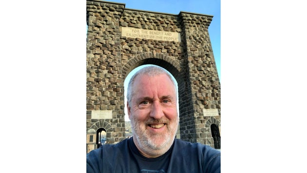 モンタナ州ガーディナーのイエローストーン国立公園北口にあるルーズベルト・アーチをくぐった筆者。乳房外パジェット病と診断されて以来、旅行は大きなストレス解消になっているという