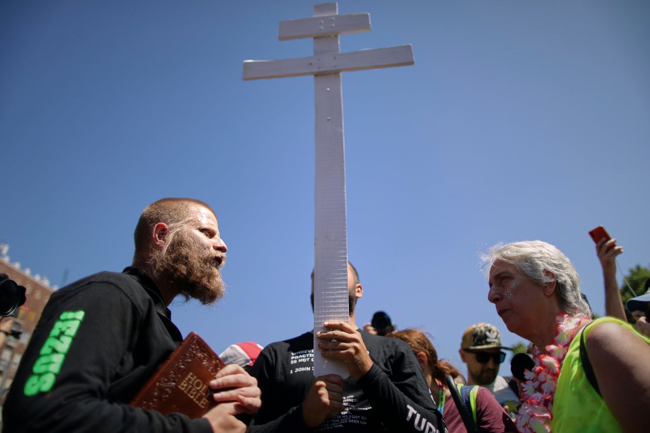 Άνθρωποι που κρατούν σταυρό και θρησκευτικά βιβλία περπατούν ανάμεσα στους συμμετέχοντες στην πορεία υπερηφάνειας στη Βουδαπέστη της Ουγγαρίας, Σάββατο 28 Ιουνίου 2025. (AP Photo/Rudolf Karancsi)