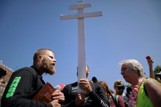 Άνθρωποι που κρατούν σταυρό και θρησκευτικά βιβλία περπατούν ανάμεσα στους συμμετέχοντες στην πορεία υπερηφάνειας στη Βουδαπέστη της Ουγγαρίας, Σάββατο 28 Ιουνίου 2025. (AP Photo/Rudolf Karancsi)
