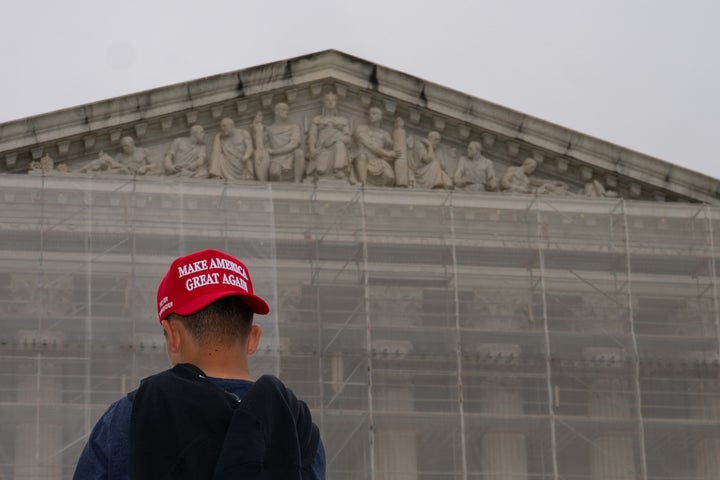 A pedestrian wears a "Make America Great Again" hat outside the Supreme Court in Washington, D.C., on June 27, 2025. The high court said on June 30, 2025, that it will take up a Republican-led appeal to erase limits on how much political parties can spend in federal elections.
