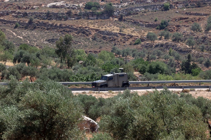 An Israeli military vehicle patrols nearby as a diplomatic delegation from the European Union inspects the damage at the West Bank village of Kafr Malik, on June 30, 2025, one day after Israeli settlers rampaged around a military base and attacked soldiers. Settlers raided the village on June 25, killing at least three Palestinians.