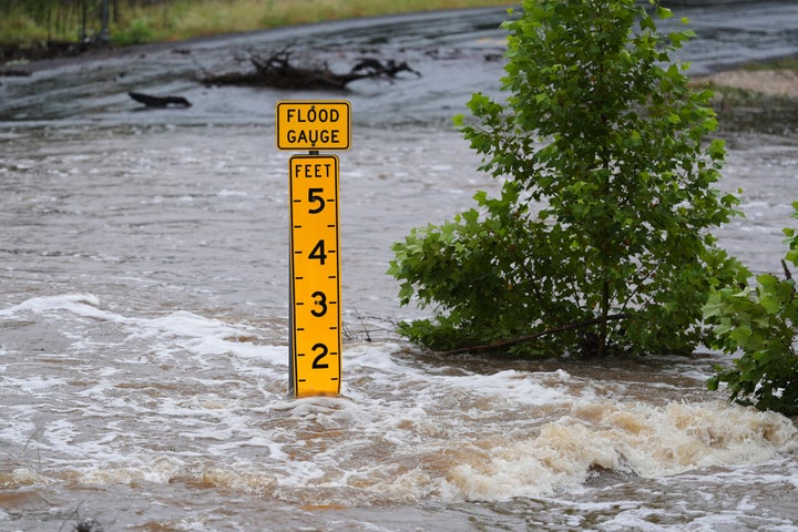 Um medidor de inundação marca a altura da água que flui sobre uma estrada de fazenda para mercado perto de Kerrville, Texas, na sexta-feira, 4 de julho de 2025. (AP Photo/Eric Gay)