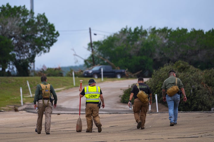 Deputies walk along a road near the Guadalupe River after a flash flood swept through the area Saturday, July 5, 2025, in Ingram. (AP Photo/Julio Cortez)