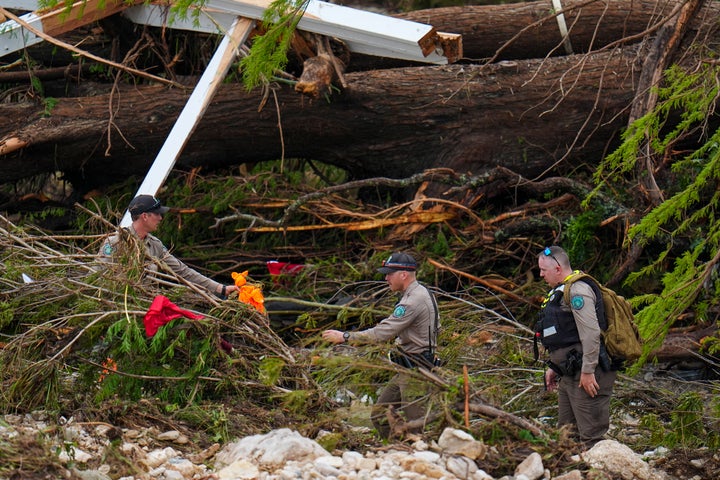 Officials with the Texas Game Warden comb through debris along the banks of the Guadalupe River after a flash flood swept through the area Saturday, July 5, 2025, in Hunt, Texas. (AP Photo/Julio Cortez)
