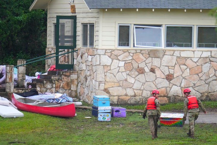 Military personnel return a camp trunk salvaged from down river to Camp Mystic along the Guadalupe River on Sunday.