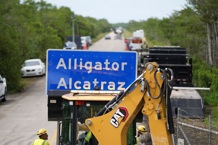 Workers install an "Alligator Alcatraz" sign Thursday at the entrance to a new migrant detention facility in Ochopee, Florida.