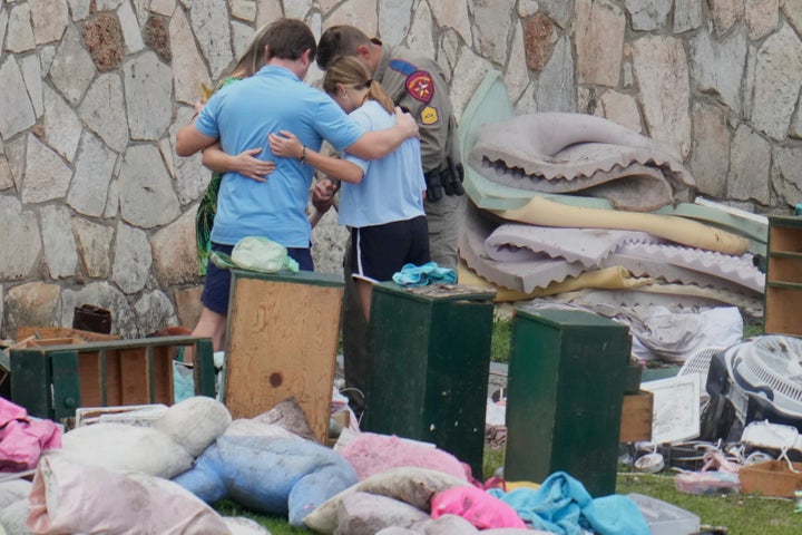 Kristi Noem Below Fireplace As FEMA Officers Blast Her Texas Flood Response 1 An officer prays with a family as they pick up items at Camp Mystic in Hunt, Texas, on Wednesday.