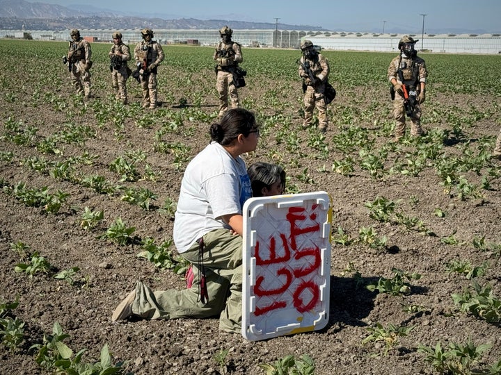 Two people kneel before federal agents during an immigration raid on July 10, 2025, in Camarillo, California. 