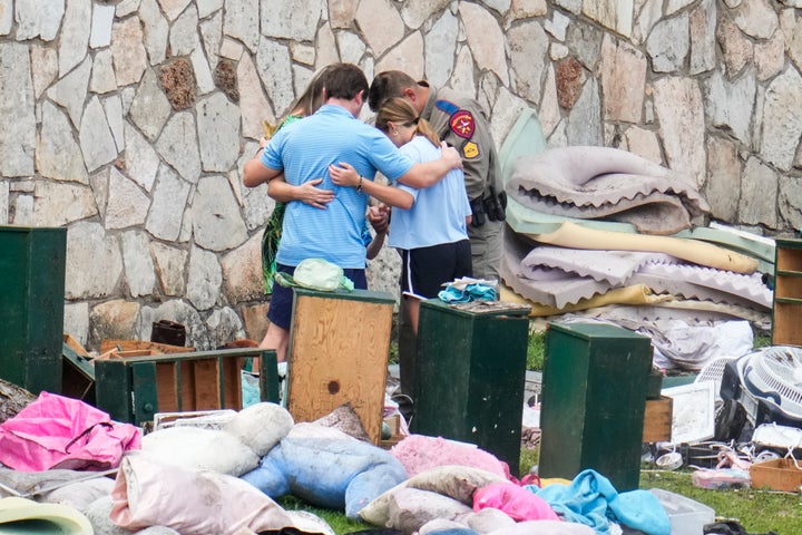 An officer prays with a family as they pick up items at Camp Mystic in Hunt, Texas on Wednesday, July 9, 2025. (AP Photo/Ashley Landis)