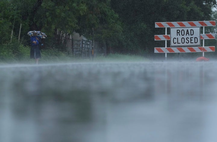 A woman walks in the rain past a closed street near the Guadalupe River, Sunday, July 13, 2025, in Kerrville, Texas. (AP Photo/Eric Gay)