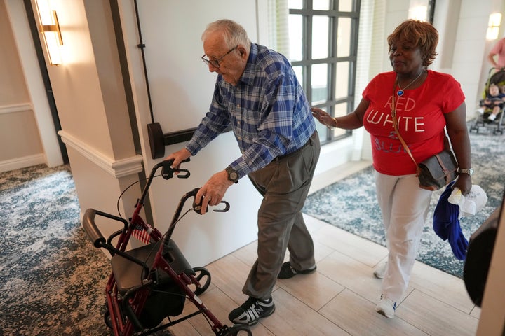 Resident Eugene Preslier, right, is accompanied by his private certified nursing aid Miriam Louis at the Toby and Leon Cooperman Sinai Residences. Nearly one in five civilian workers in the U.S. is foreign born, but immigrants are overrepresented in caregiving roles.